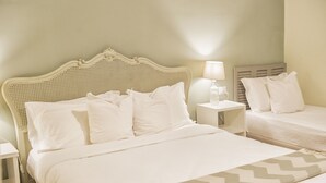 Una habitación de hotel con una cama grande, dos mesitas de noche y una mesita auxiliar con una lámpara.