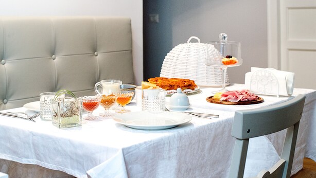 Una mesa de desayuno dispuesta con platos, vasos y diversos alimentos.