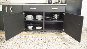 Una cocina con encimera negra, un lavabo y un refrigerador.