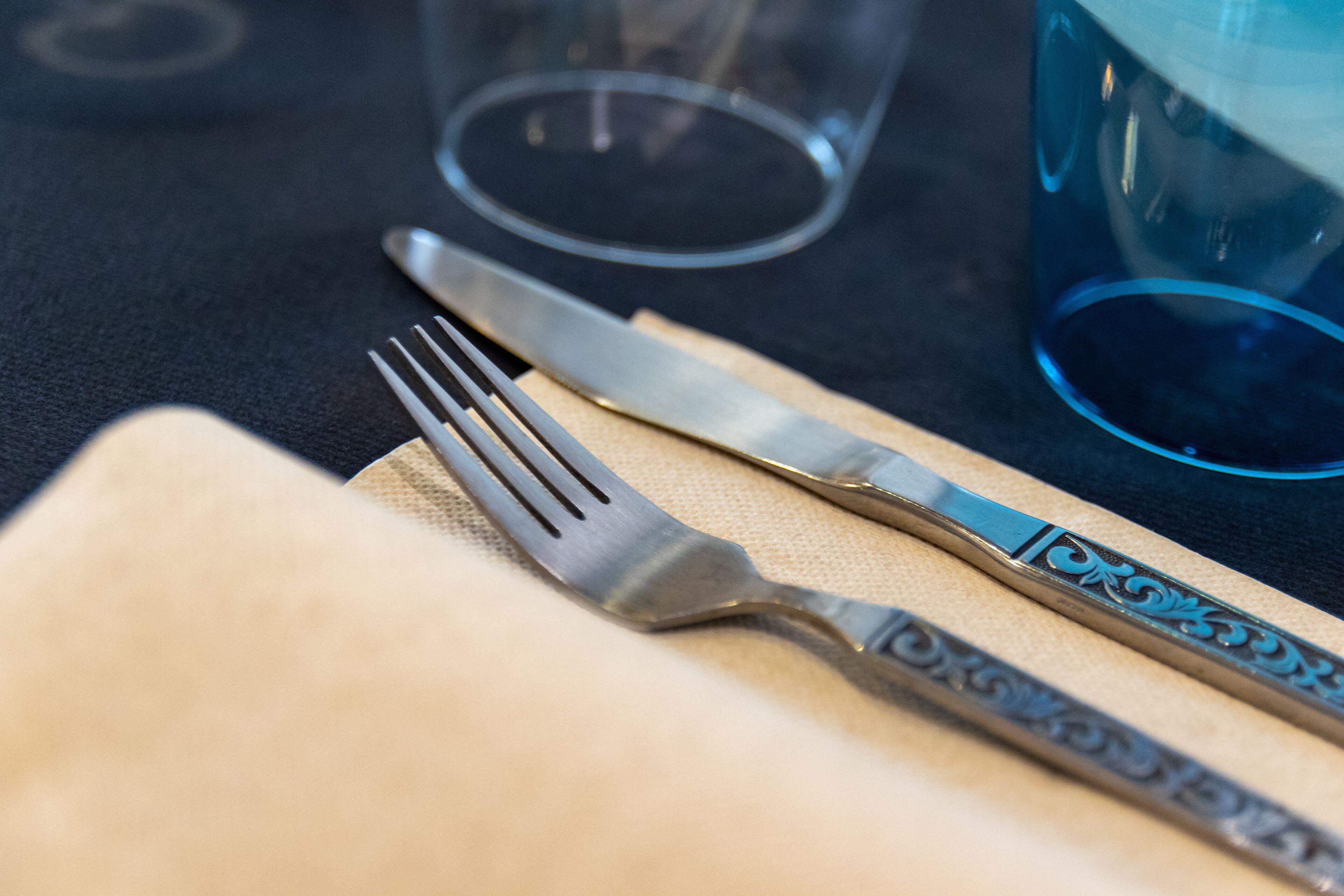 A table setting with a fork, knife, and a blue glass.
