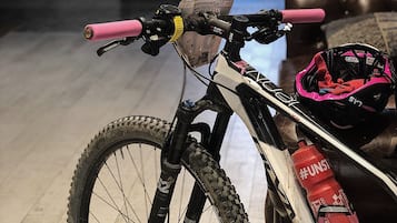 A mountain bike with a pink handlebar and a helmet on the floor.