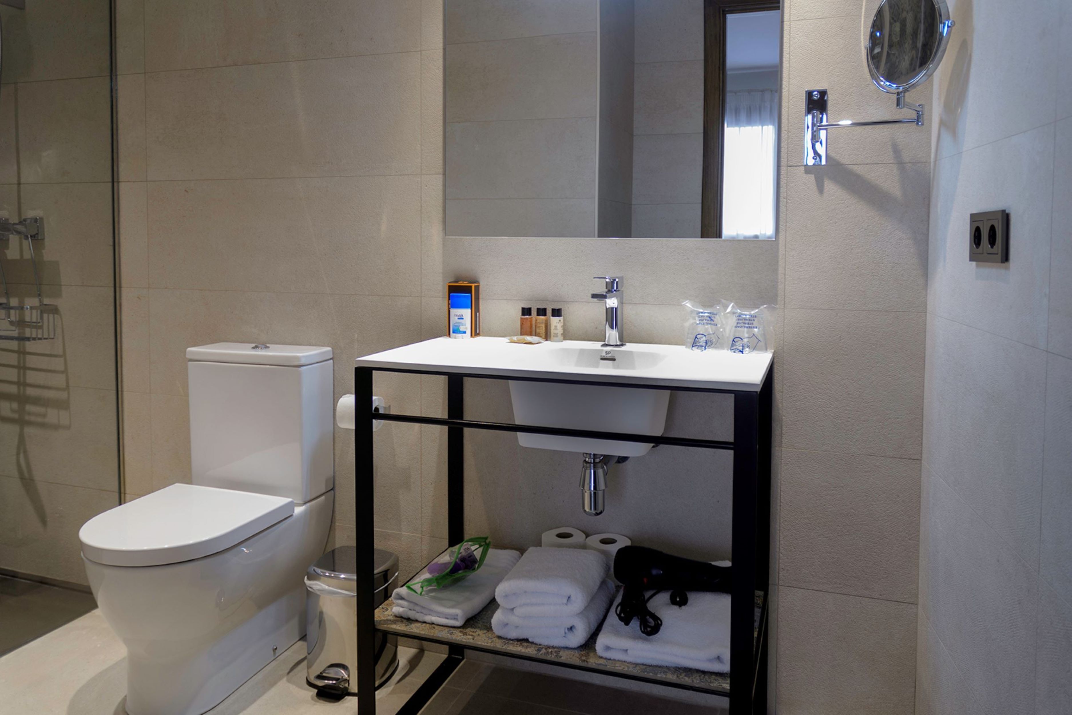 Un baño moderno con inodoro, lavamanos y espejo.