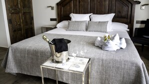 Una cama bien hecha con cabecera de madera, una mesita de noche con una botella y vasos, y una toalla decorativa sobre la cama.
