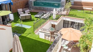 Un área de piscina en la azotea con un jacuzzi, sillones de descanso y una zona de bar.