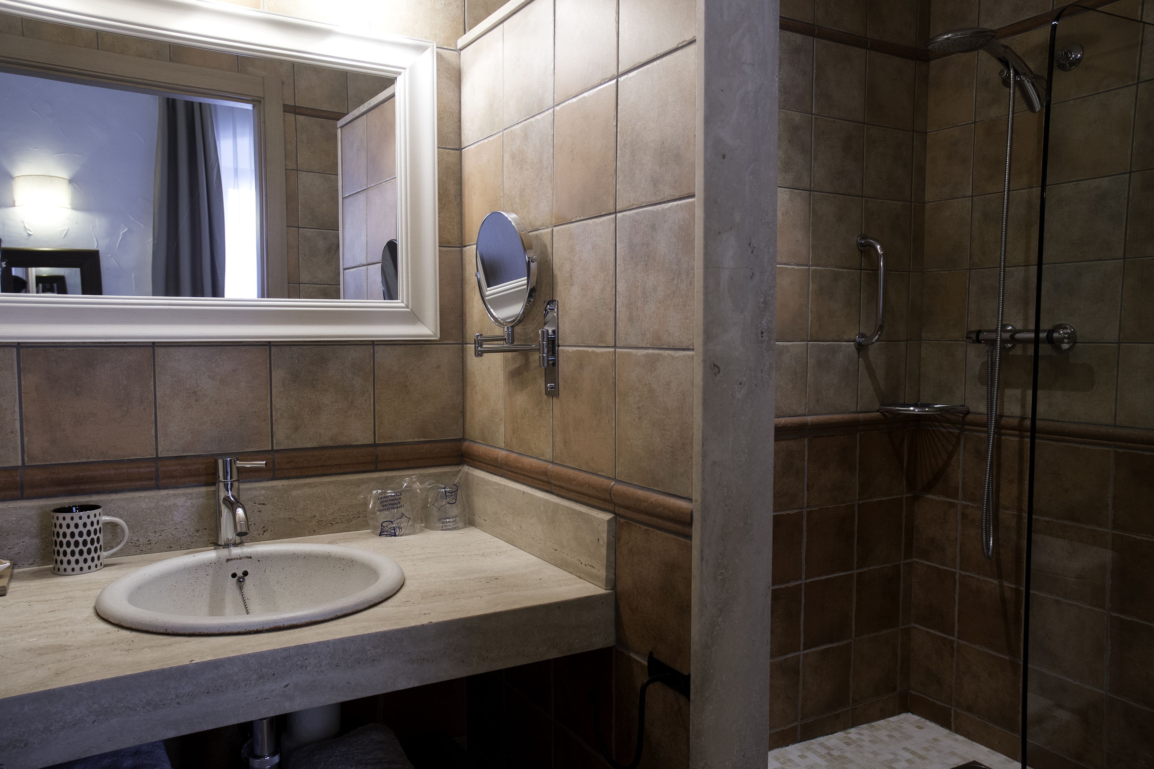 Un baño con lavamanos, espejo y ducha.