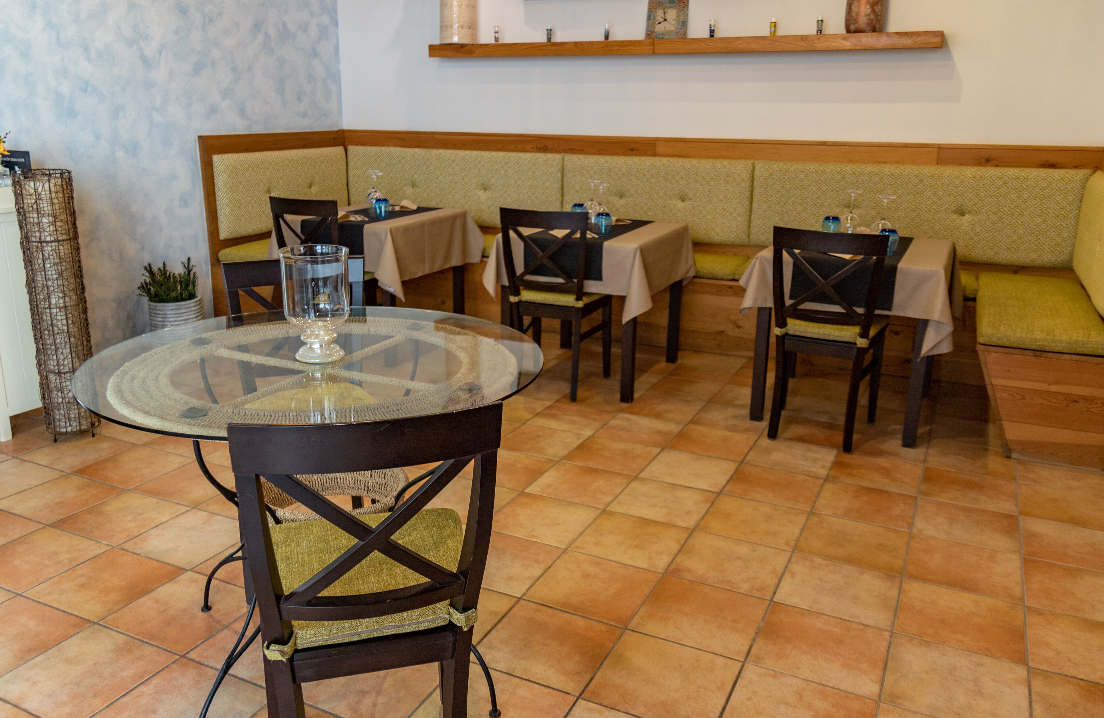 Un interior de restaurante con mesas redondas, asientos acolchados y suelo de baldosas.