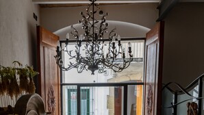 Un pasillo amplio con una lámpara de candelabro grande, una planta en maceta y un armario de madera.