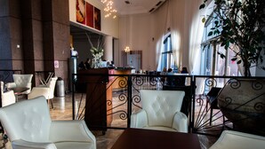 A hotel lobby with a reception desk, seating area with white leather chairs, and a large window with a view. - Apartment on the Beach (Haifa)