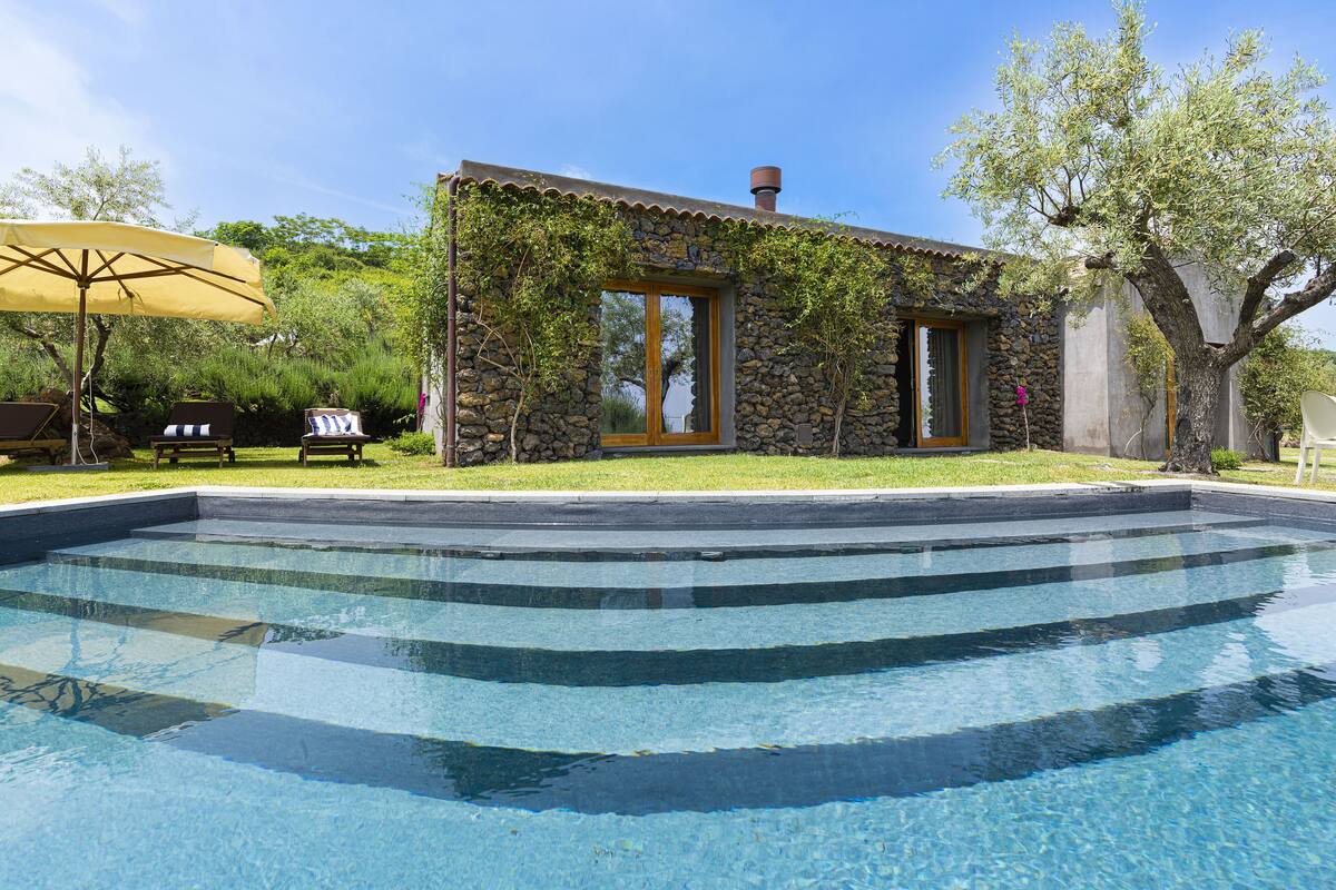 Un bâtiment en pierre avec une piscine devant.