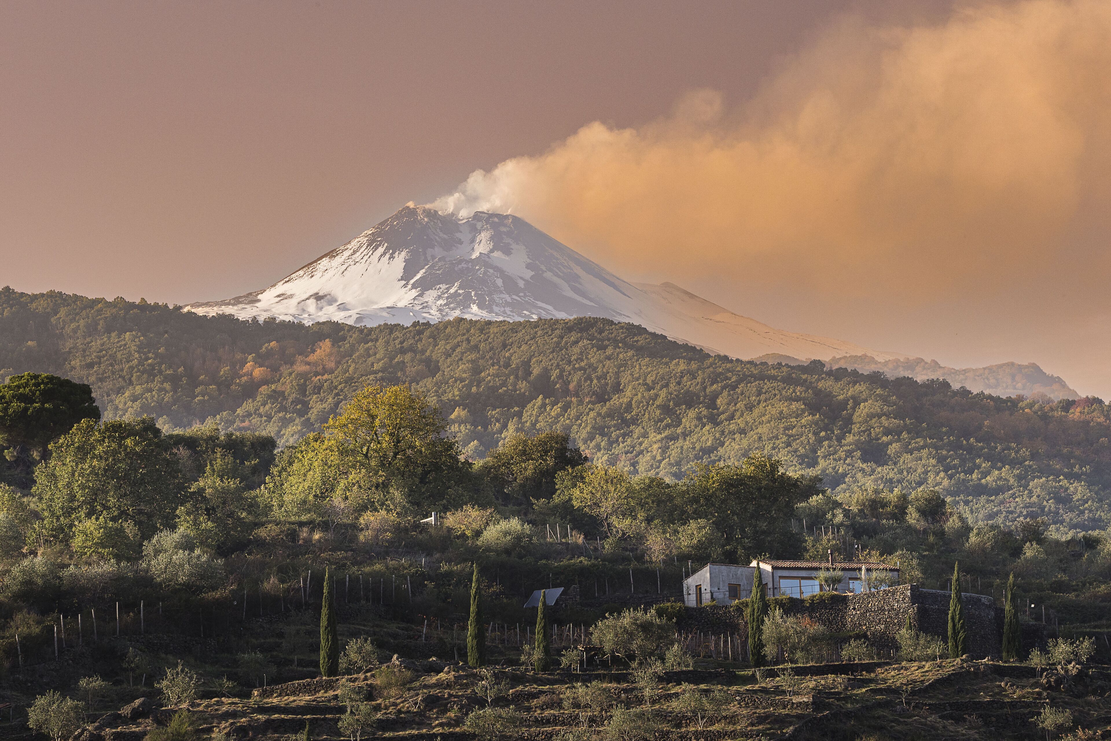 Une montagne dont le sommet est enneigé, avec une maison au premier plan.
