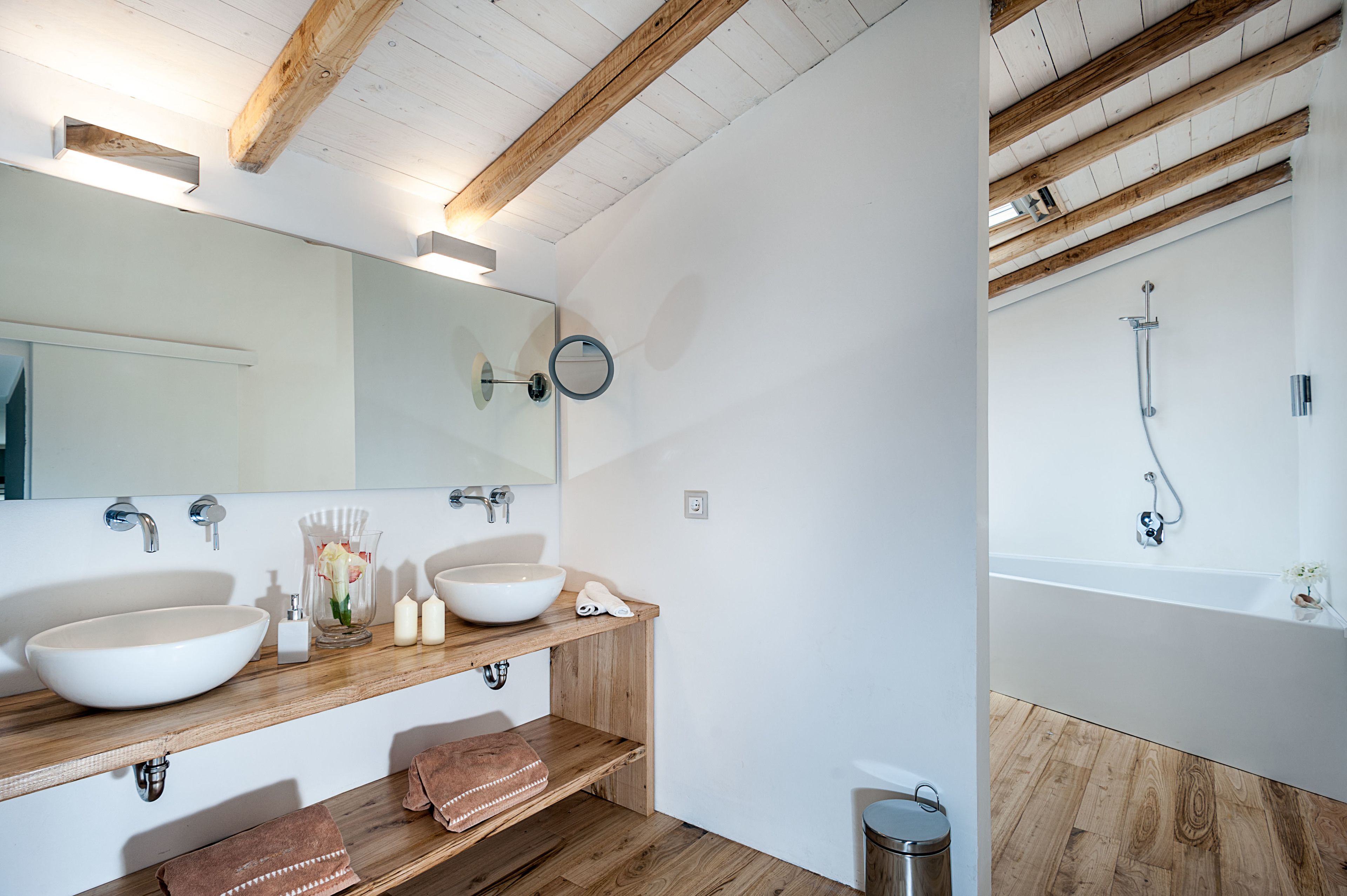A modern bathroom with two sinks, a large mirror, and a bathtub.