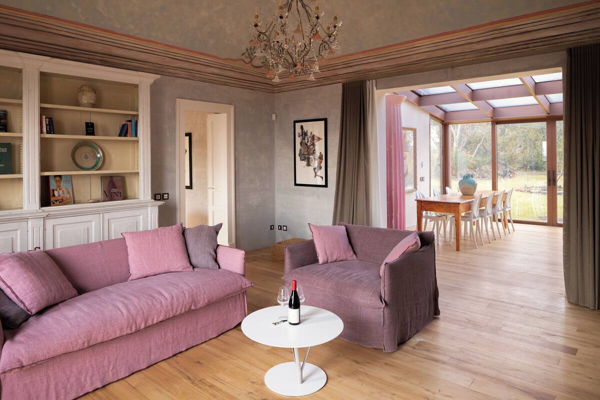 Un salon avec un canapé, un fauteuil et une petite table sur laquelle se trouvent une bouteille et des verres.