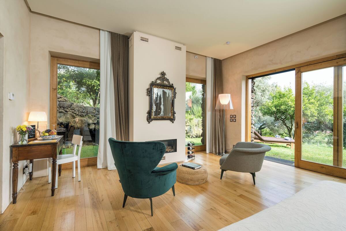 Un vaste espace de vie doté d’un plancher en bois, d’une cheminée, d’une table à manger avec des chaises et de grandes fenêtres offrant une vue sur l’extérieur.