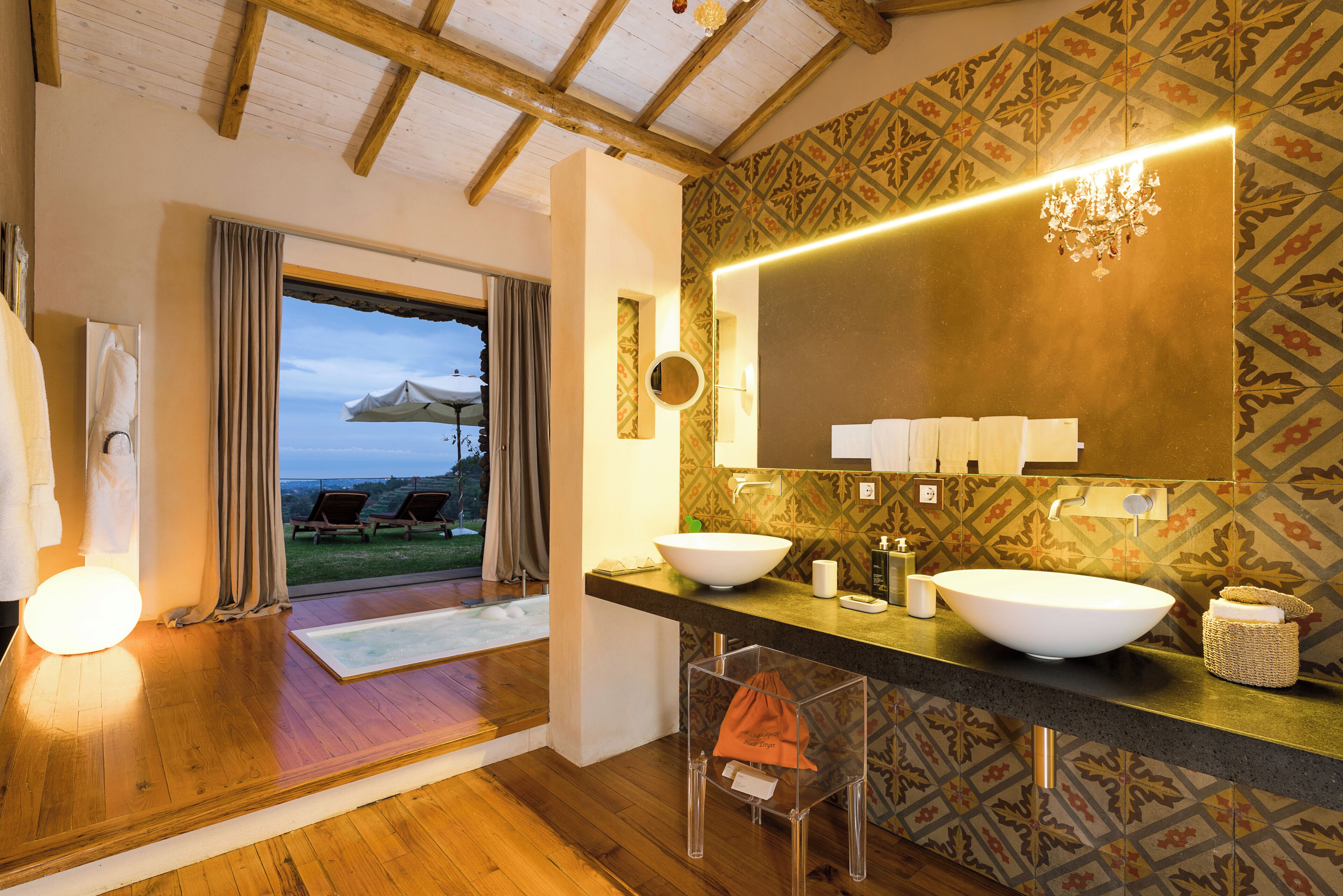 A bathroom with a large mirror, two sinks, and a view of the outdoors.