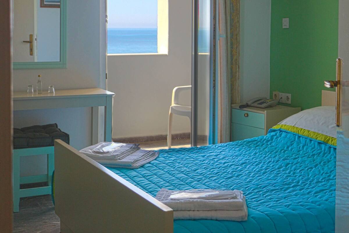 A bedroom with a bed, a window with curtains, a bedside table, and a nightstand.