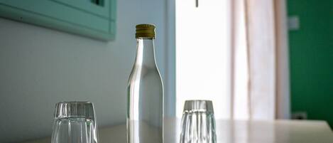 Une bouteille en verre transparent et deux verres sur une table.