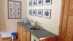 Una cocina con armarios de madera, encimera de granito, un lavamanos y un cartel con peces en la pared.