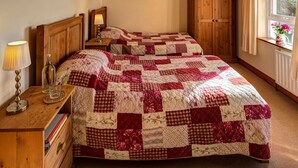 Un dormitorio con dos camas, cabeceros de madera, una mesita de noche con lámpara, un aparador de madera y una ventana con vistas.