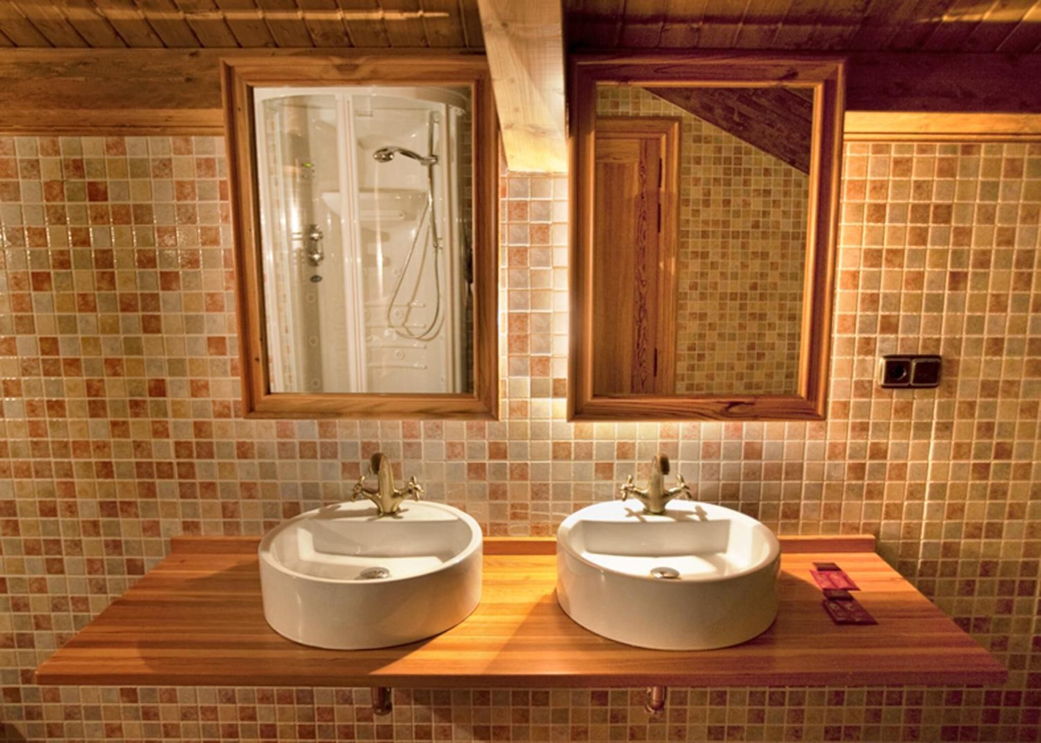 Un baño con dos lavamanos, una ducha y un espejo.