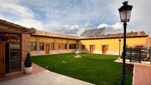 Un patio con una fuente, edificios amarillos y un panel solar.