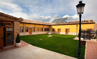 Un patio con una fuente, edificios amarillos y un panel solar.