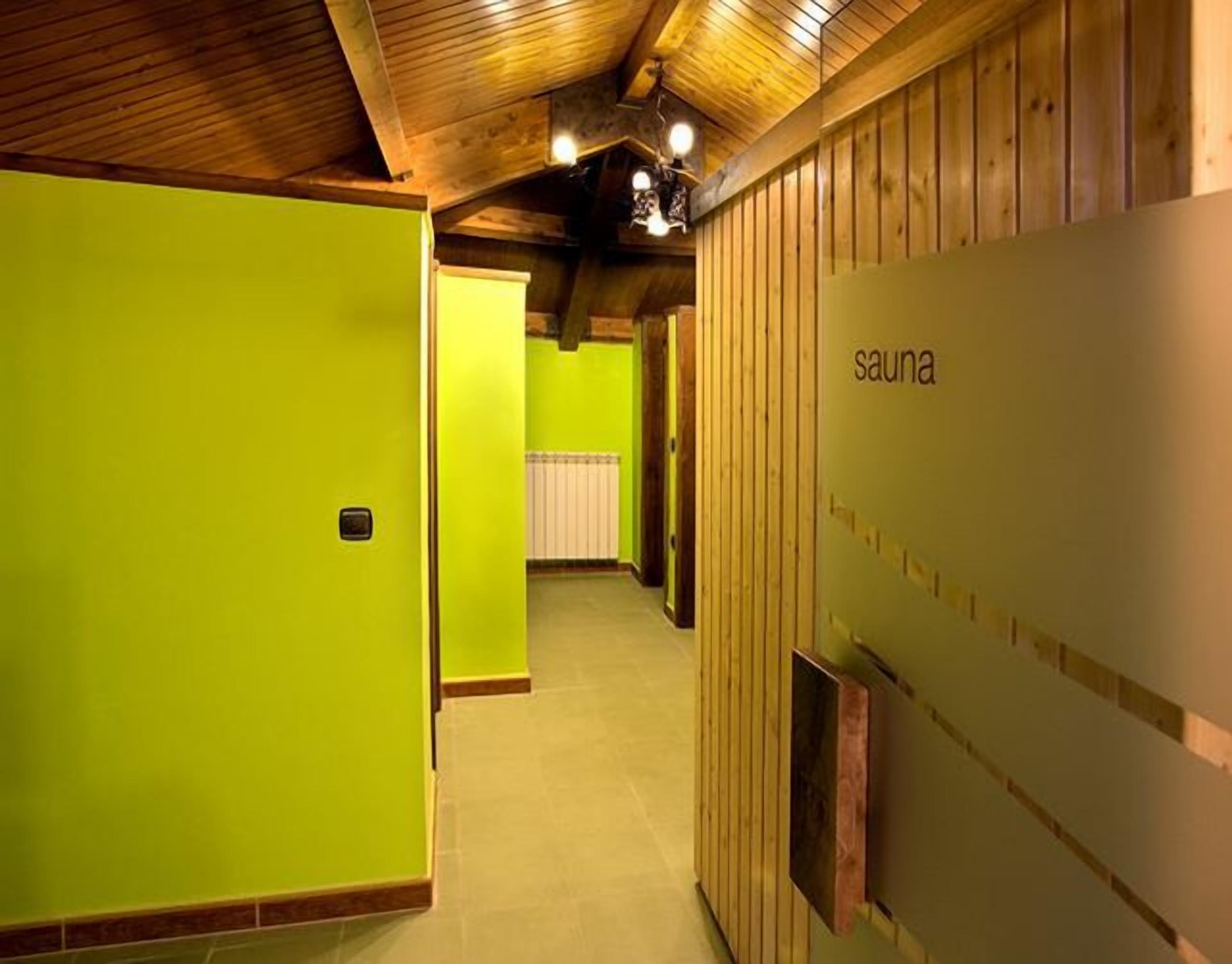 A hallway with wooden walls and a green door, leading to a sauna area.