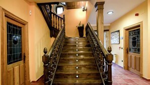 Una escalera de madera con barandilla que lleva a un rellano con una planta en maceta.
