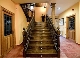 Una escalera de madera con barandilla que lleva a un rellano con una planta en maceta.