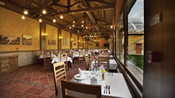Un restaurante con vigas de madera, pisos de baldosas y mesas dispuestas para comer.