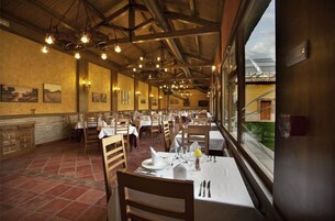 Un restaurante con vigas de madera, pisos de baldosas y mesas dispuestas para comer.