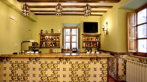 Una zona de bar con un salpicadero de azulejos con diseño de pájaros, vigas de madera en el techo y una ventana a la derecha.