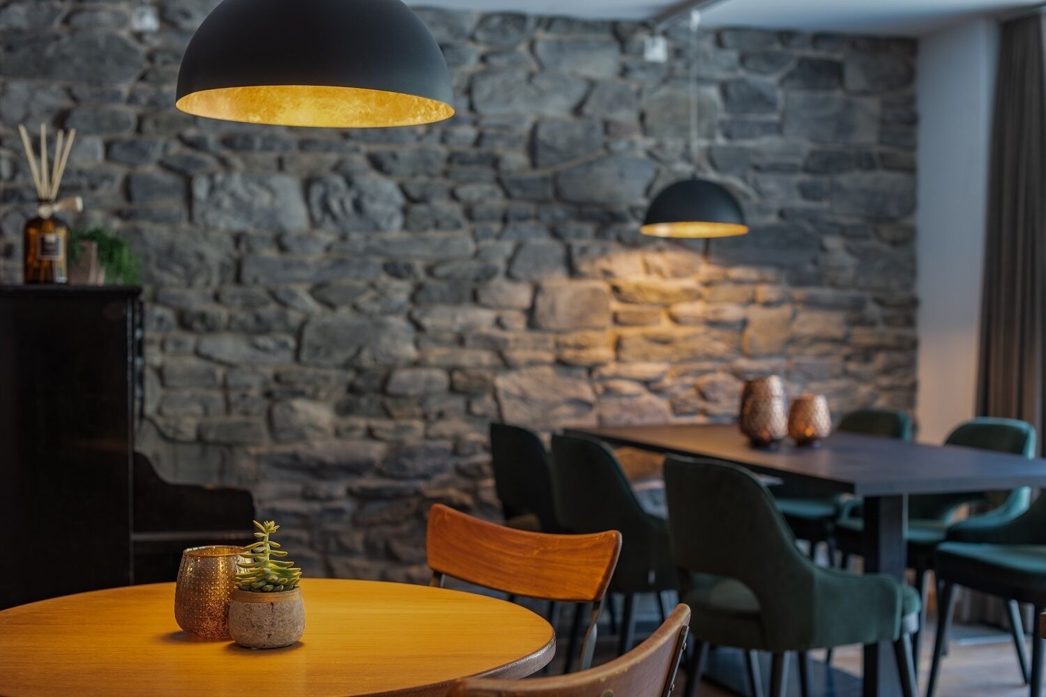 A restaurant interior with a stone wall, wooden tables, and chairs.