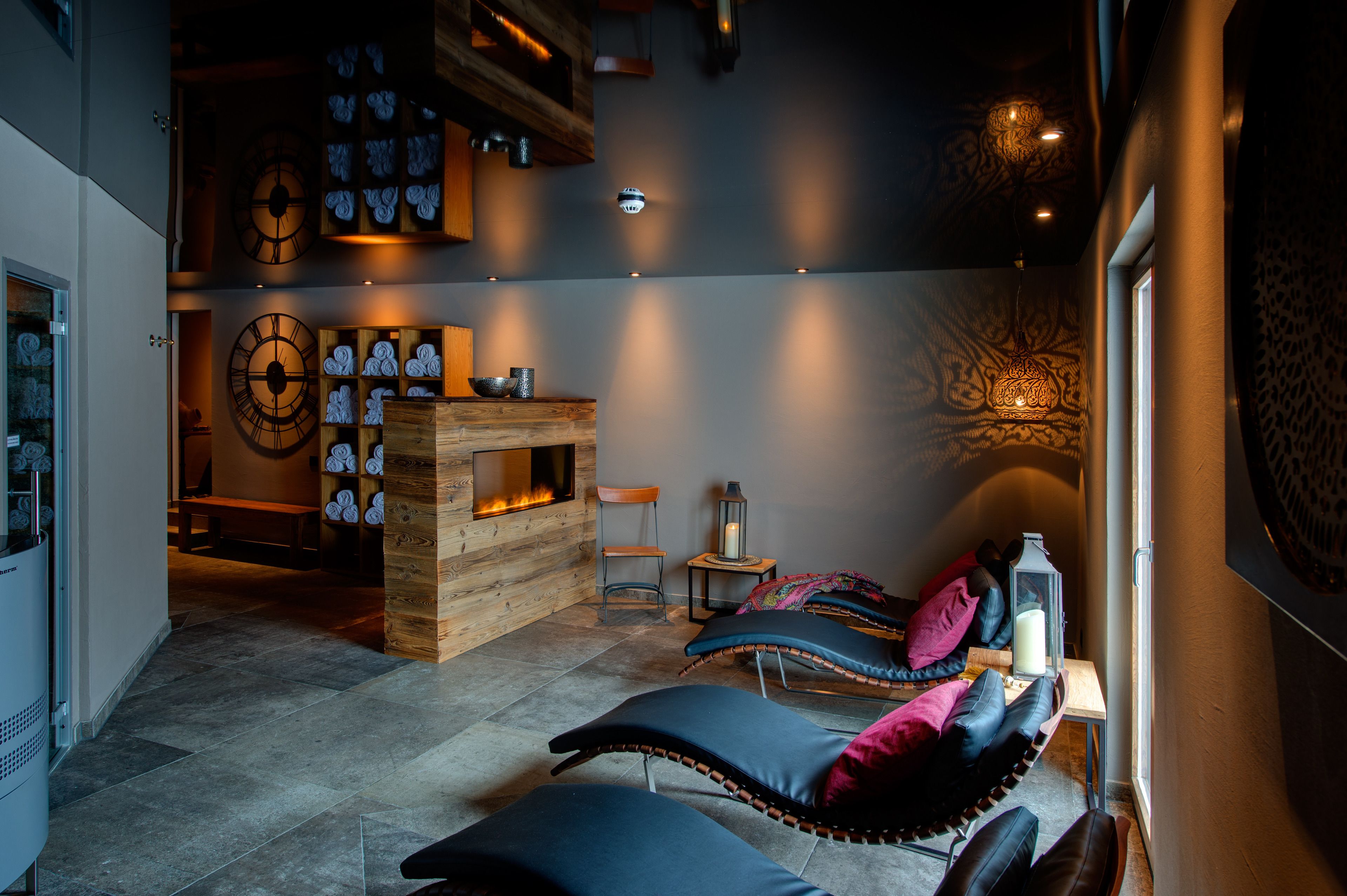 Una habitación acogedora con chimenea, asientos cómodos y relojes de pared decorativos.