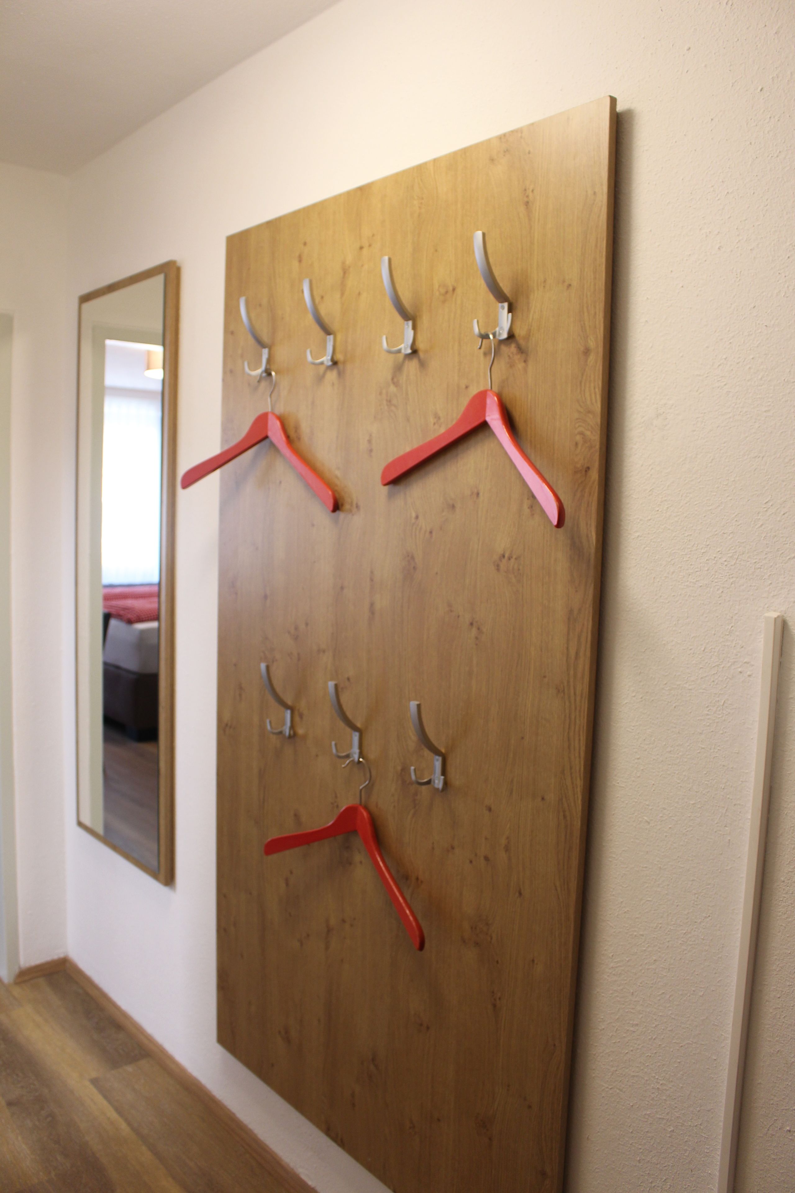 A wooden wall with multiple metal hooks for hanging items.