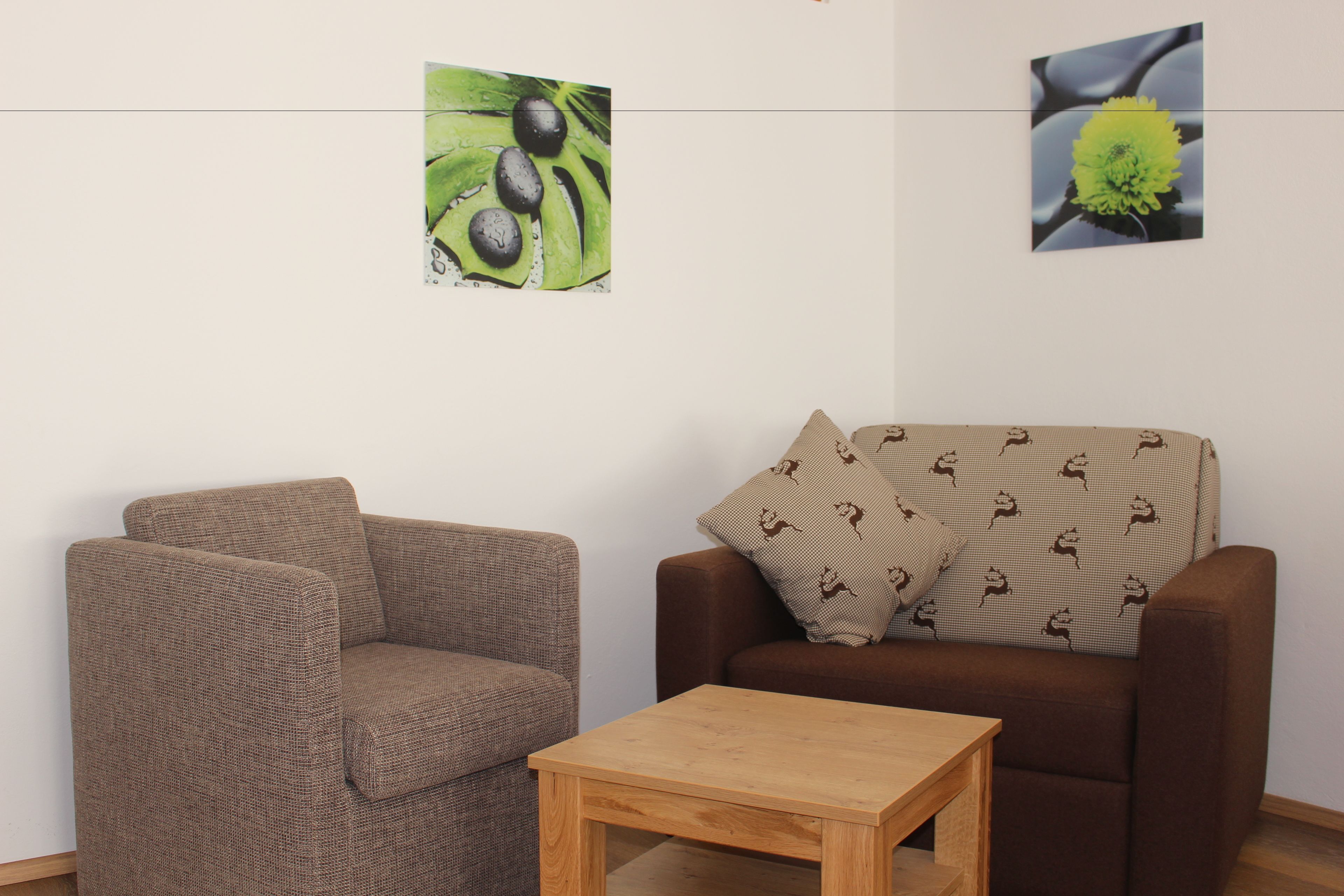 A living room with a brown sofa, a wooden coffee table, and two wall-mounted pictures.