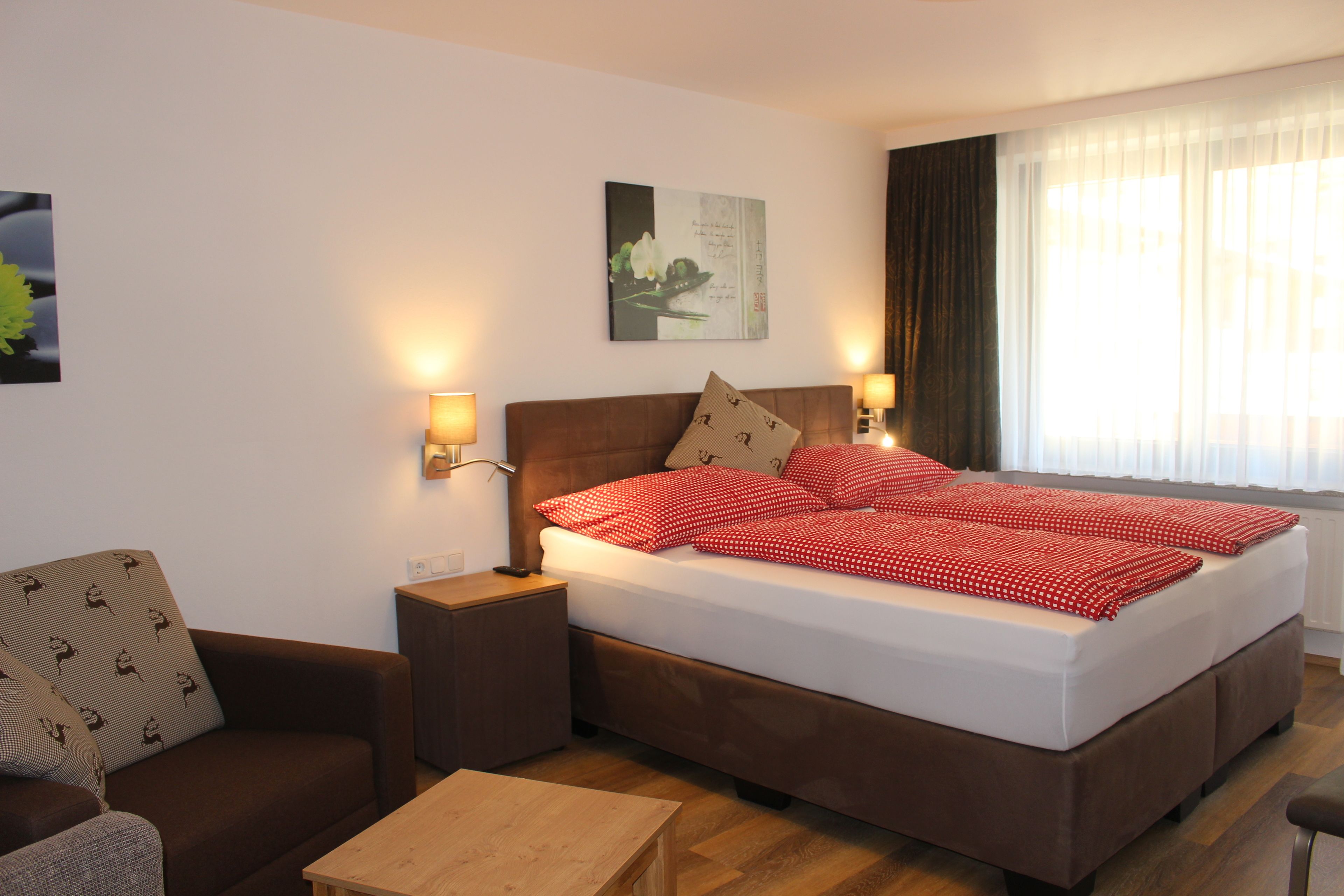 A neatly arranged hotel room with a bed, a sofa, a nightstand, and a table.