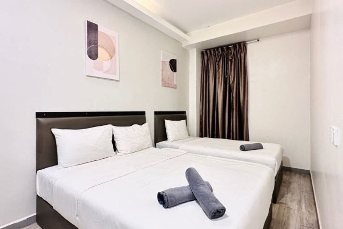 A hotel room with two beds, a large window with curtains, and artwork on the walls.