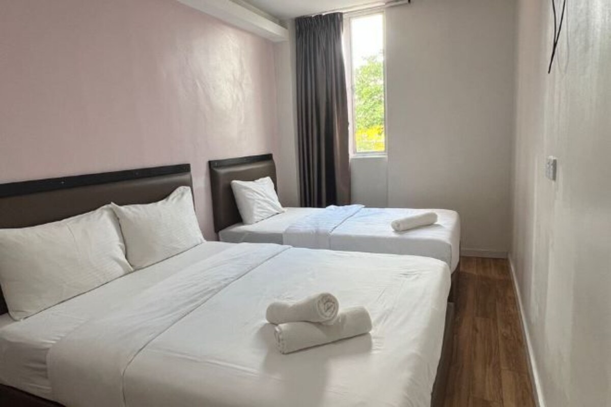 Una habitación de hotel con dos camas individuales, una ventana con cortinas y piso de madera.