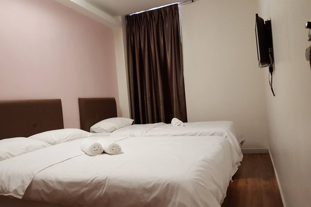 Une chambre d’hôtel avec deux lits, une tête de lit, un rideau et un téléphone fixé au mur.