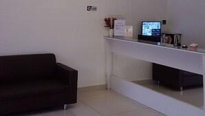 Een moderne receptiebalie met een donkere bank, een witte console en een kroonluchter.
