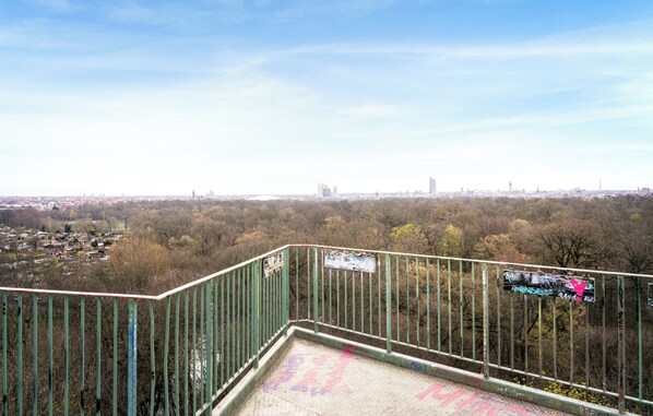 A view from a high vantage point overlooking a cityscape with a mix of residential and commercial buildings, a bridge, and a distant tower.