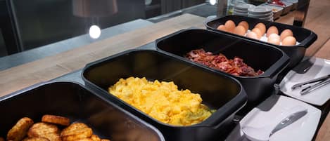 A buffet with various food items including scrambled eggs, bacon, and roasted potatoes.