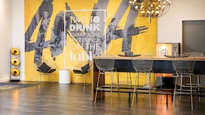 A modern bar area with a large mural, bar stools, and a chandelier. - elaya hotel leipzig city center (Leipzig)