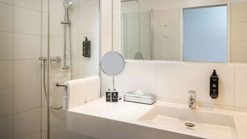 A modern bathroom with a glass shower enclosure, a sink with a mirror, and toiletries.