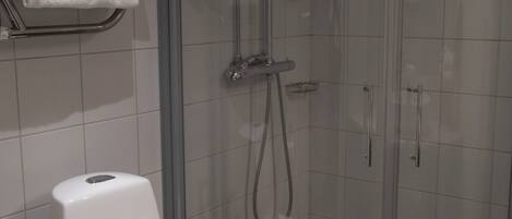 Baño con inodoro, cabina de ducha y barra para toallas.