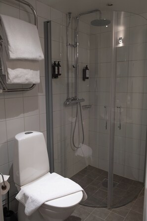 A bathroom with a toilet, a shower enclosure, and a towel rack. - Hotel Åregården (Åre)