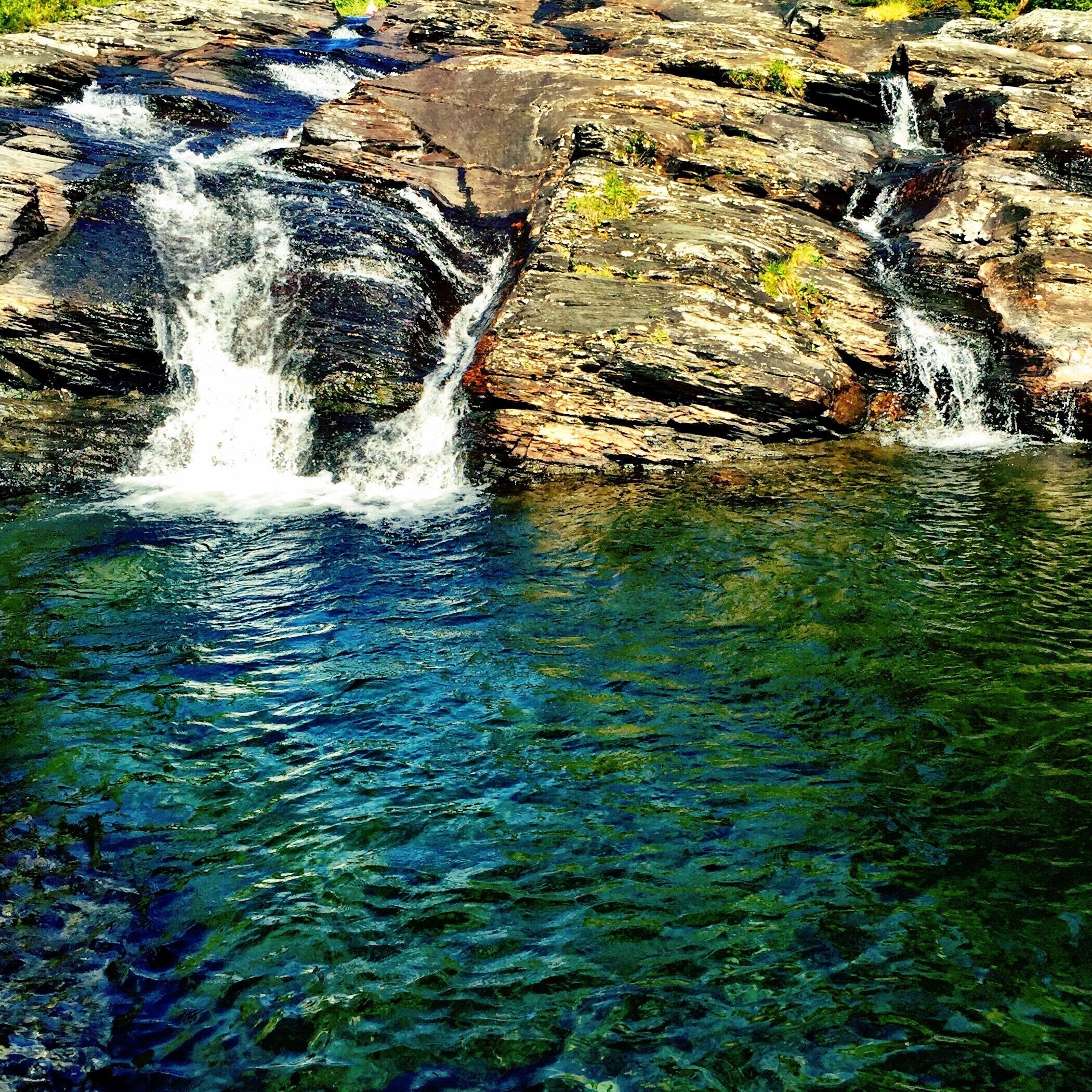 Un cuerpo de agua cristalina con una cascada rocosa.