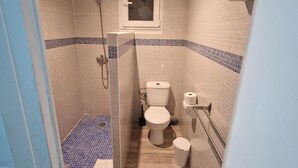 A small, tiled bathroom with a shower, toilet, and a window. - Hostal Sol de Mallorca. (Palma de Mallorca)