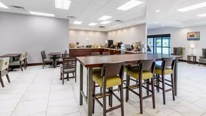 A spacious dining area with multiple tables and chairs, a central counter, and a kitchen in the background. - Days Inn and Suites by Wyndham Oxford (Oxford)