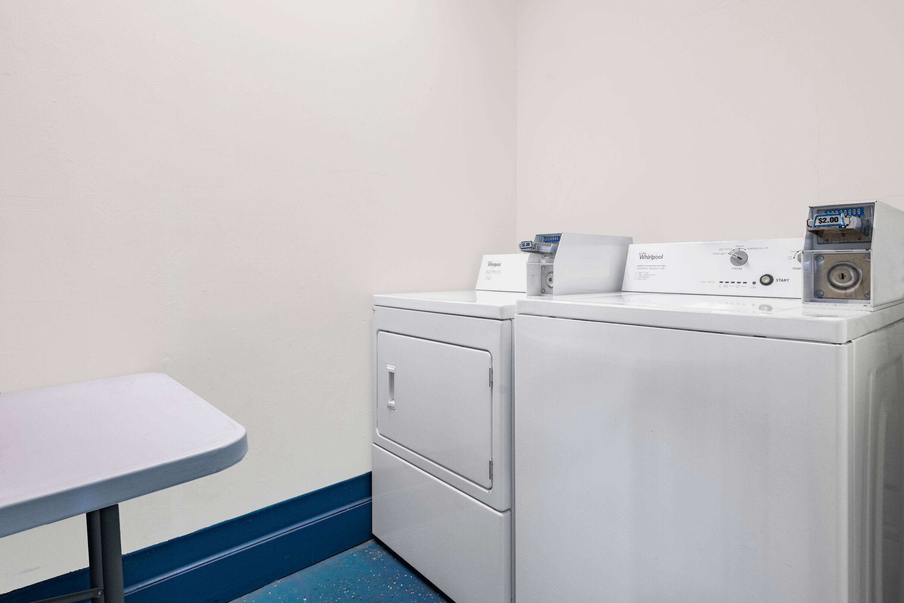 Une buanderie équipée de deux lave-linge Whirlpool blancs et d’une table.